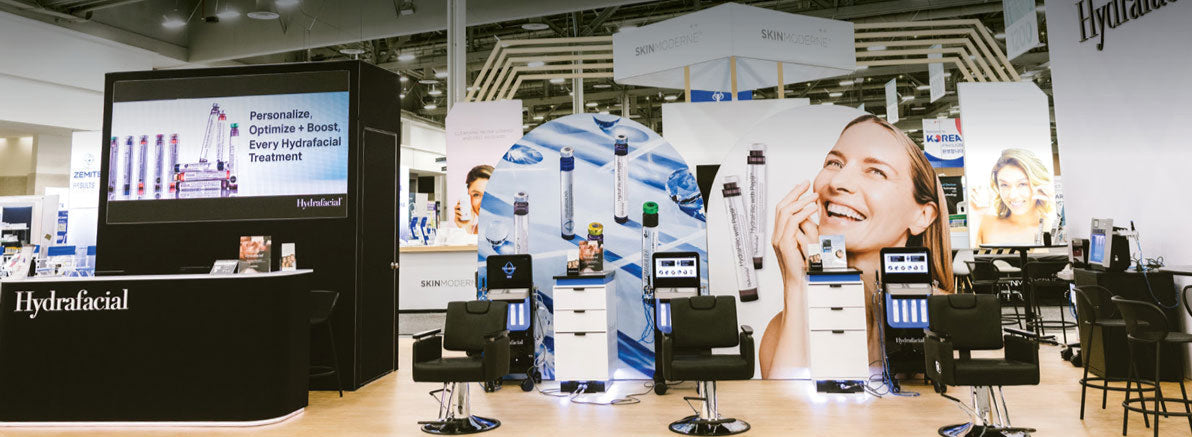 Hydrafacial tradeshow booth featuring treatment stations, promotional displays, and large product imagery with bright visuals of glowing skin.