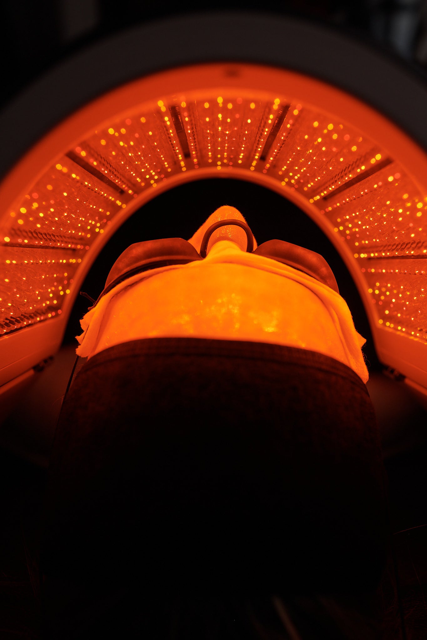 Close-up side view of a black-gloved hand holding a Hydrafacial device with a clear tip against the chin area.