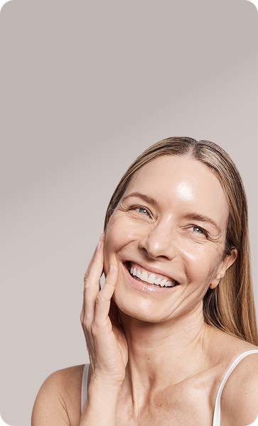 Close-up of a woman laughing with eyes closed, her skin appearing luminous and hydrated.