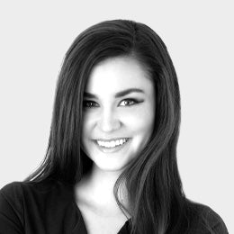 Black-and-white professional headshot of Abigail Quinn, an esthetician, with long straight hair, smiling and wearing a dark top.
