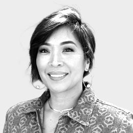 Black-and-white professional headshot of Tiffany Libiran, an esthetician, with short layered hair, wearing a patterned jacket and necklace, smiling.