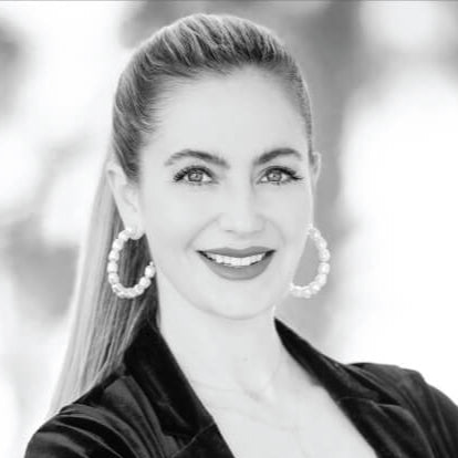Black-and-white portrait of Dr. Heidi Prather a dermatologist, wearing hoop earrings and a velvet jacket.