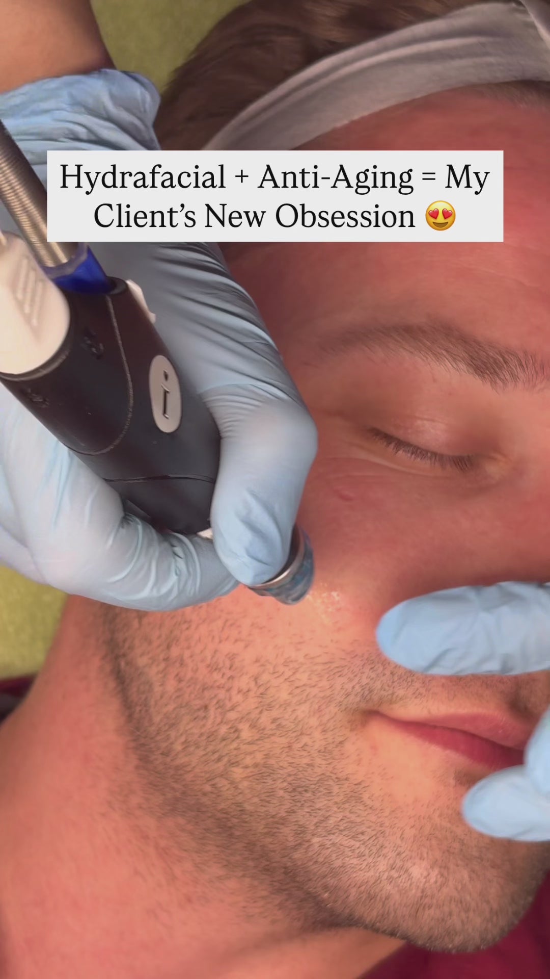 Close-up of a male client receiving a Hydrafacial treatment. A provider in blue gloves applies the turquoise-tipped device along his cheek as the client relaxes with eyes closed. Overlay text reads: “Hydrafacial + Anti-Aging = My Client’s New Obsession.”